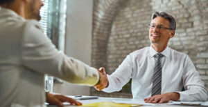 Reduzir Riscos Fiscais: reunião com aperto de mãos, representando suporte contábil, regularidade e segurança fiscal para pequenos negócios.