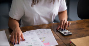 Organização Fiscal da Sua Empresa: pessoa conferindo relatórios e calculadora, representando controle fiscal, prazos e prevenção de multas na empresa.