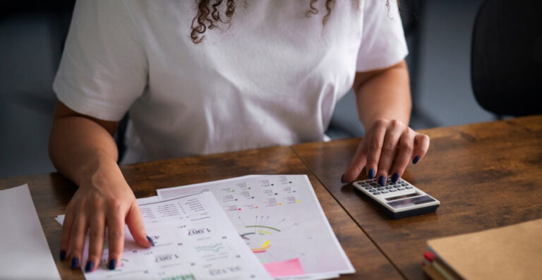 Organização Fiscal da Sua Empresa: pessoa conferindo relatórios e calculadora, representando controle fiscal, prazos e prevenção de multas na empresa.