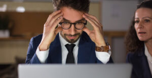 O que são Obrigações Acessórias: empresário preocupado analisando dados no notebook, representando risco fiscal e importância das obrigações acessórias.