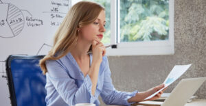 Obrigações Fiscais para Pequenas Empresas: empresária analisando relatórios no escritório, representando controle fiscal e rotina de obrigações em 2026.